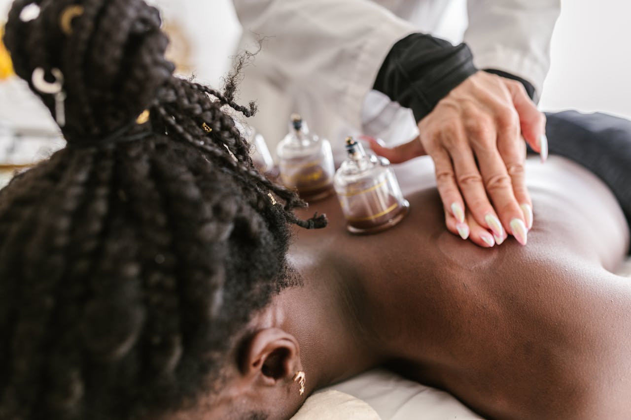 An adult woman receiving soothing cupping therapy by a professional masseuse in a calm spa setting.